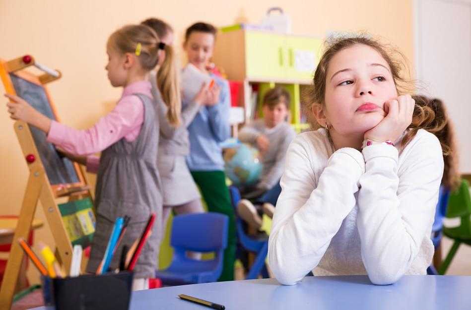 Sad bored schoolgirl in classroom at break