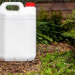 white blank plastic jerry can for garden plant fertilizer in flower bed