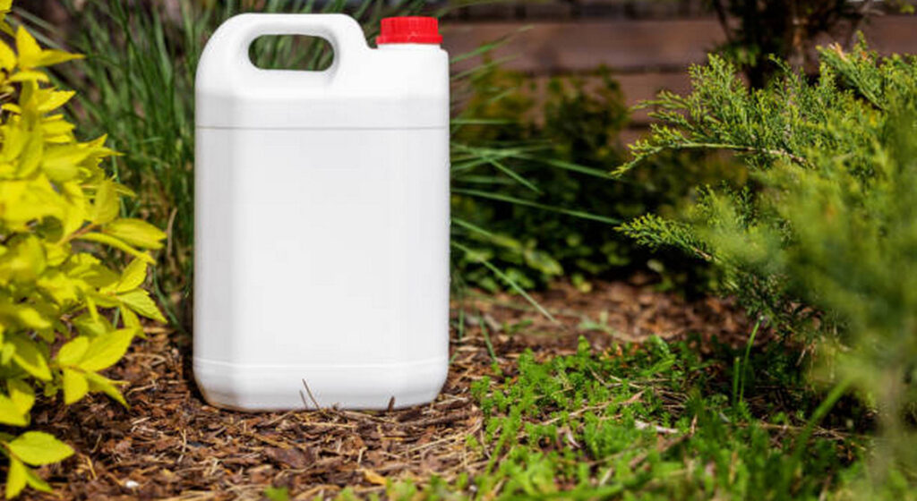 white blank plastic jerry can for garden plant fertilizer in flower bed